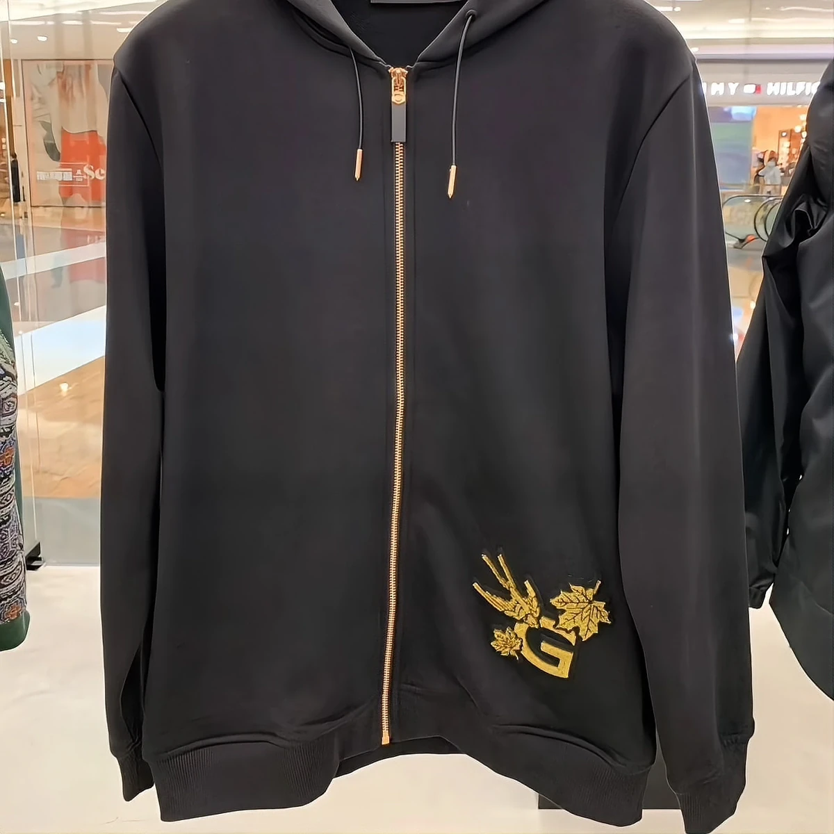 GIVENCHY black hoodie with gold-thread embroidered patch on display in a boutique