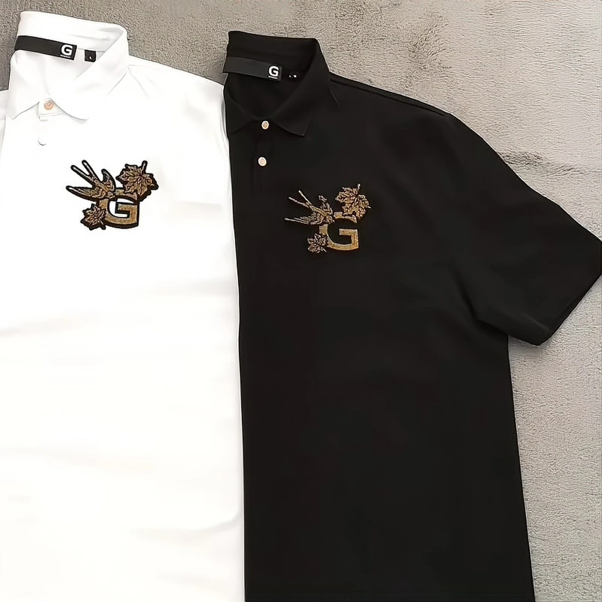 Close-up detail of GIVENCHY black-and-white two-tone polo with gold-thread toothbrush embroidery patch